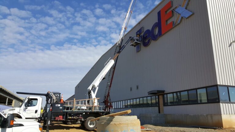 MRC Signs crew installing FedEx channel letters with a crane truck